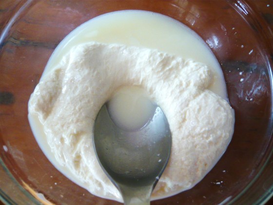 Kneading heated cheese and pouring off whey.